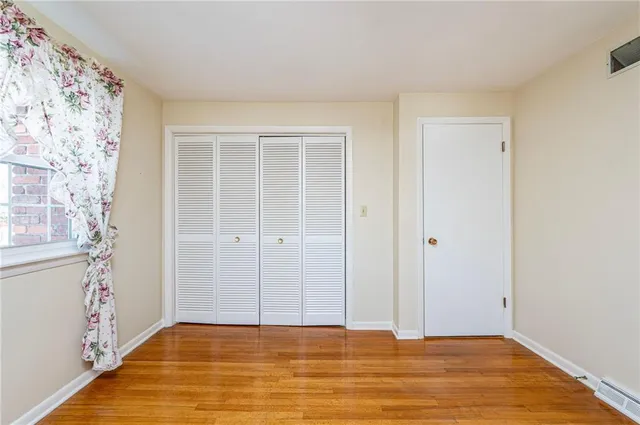 a view of an empty room with cabinet and wooden floor