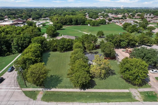 a view of a green field with lots of trees in the background