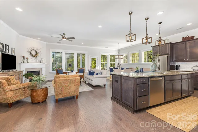 a large living room with stainless steel appliances kitchen island granite countertop a large kitchen a sink dishwasher a dining table and chairs with wooden floor