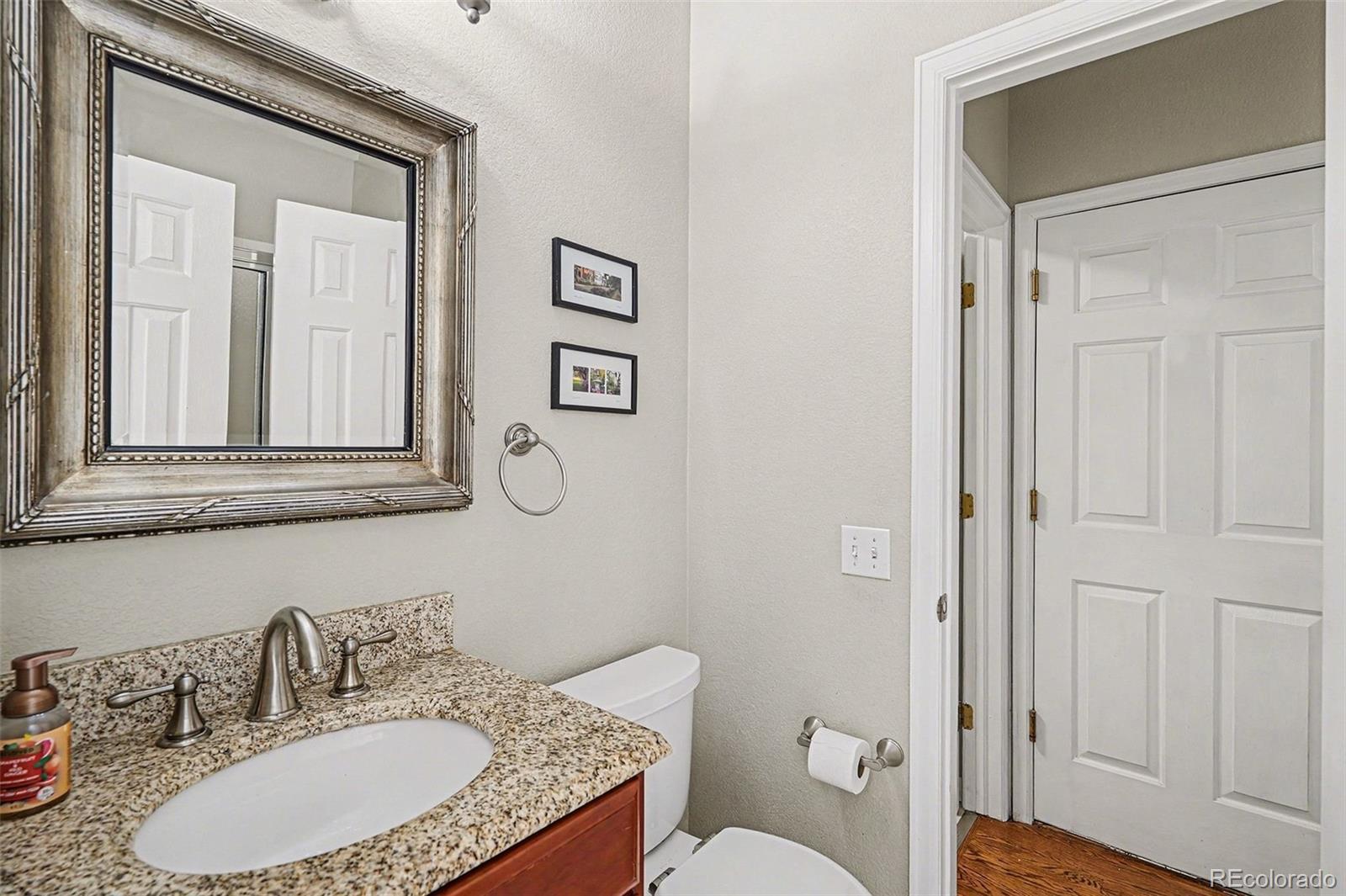 8046 Lodgepole Trail Lone Tree, CO 80124 - Photo 17 of 34 a bathroom with a granite countertop toilet a sink and a mirror