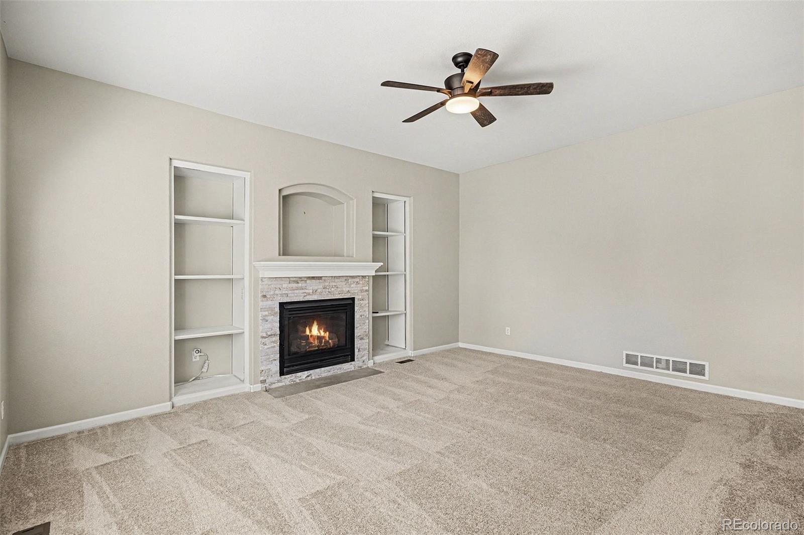 8046 Lodgepole Trail Lone Tree, CO 80124 - Photo 6 of 34 a view of a livingroom with a fireplace a ceiling fan and window