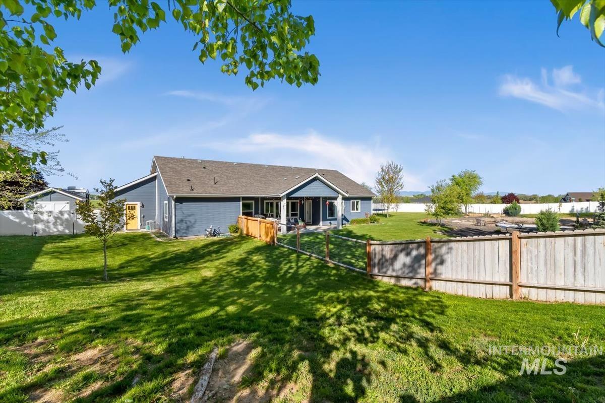 15015 Leon Lane Caldwell, ID 83607 - Photo 31 of 44 Expansive rear yard featuring a manicured lawn, established landscaping, and a partial wood privacy fence