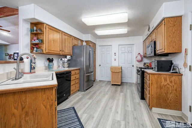 a kitchen with stainless steel appliances granite countertop a refrigerator a stove top oven a sink dishwasher and wooden cabinets with wooden floor
