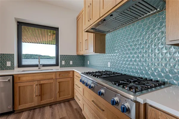 a kitchen with a stove a sink and wooden floor