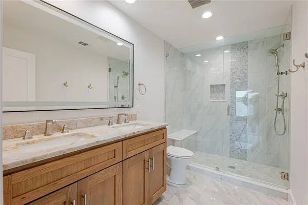 a bathroom with a granite countertop sink a toilet and shower
