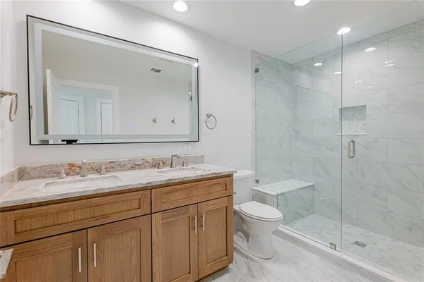 a bathroom with a toilet a sink a mirror and shower
