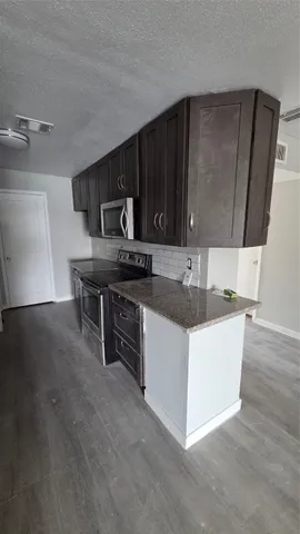 a living room with stainless steel appliances a fireplace a rug and a counter top space