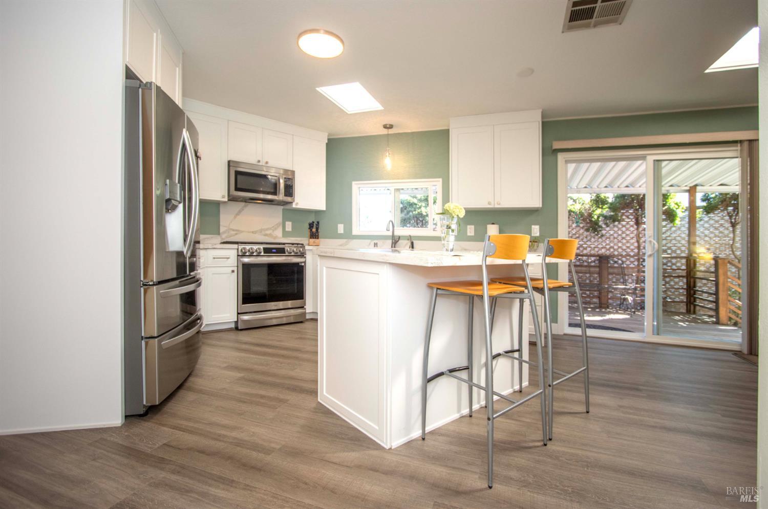 9 Fallen Leaf Way Novato, CA 94949 - Photo 4 of 32 a kitchen with stainless steel appliances granite countertop a stove top oven a sink dishwasher a dining table and chairs with wooden floor