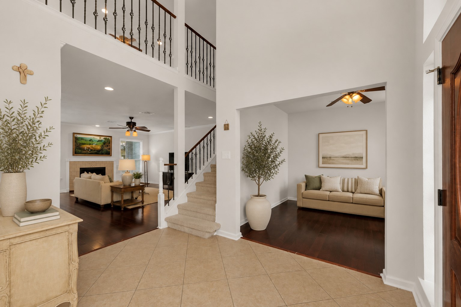 12528 Labrador Cove Austin, TX 78729 - Photo 4 of 40 Virtually Staged | Grand two-story foyer with soaring ceilings, dramatic staircase, rich hardwood flooring, and abundant natural light, opening to a Pottery Barn-inspired formal living space that showcases the home’s exceptional scale, flexible living areas, and timeless architectural appeal. Furnishings, artwork, plants, and décor are virtually staged and shown for illustrative purposes only.