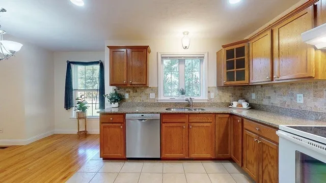 a kitchen with stainless steel appliances granite countertop wooden cabinets a sink and dishwasher a oven with wooden floors
