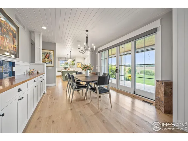 a view of a dining room and livingroom with furniture wooden floor a potted plant and a chandelier