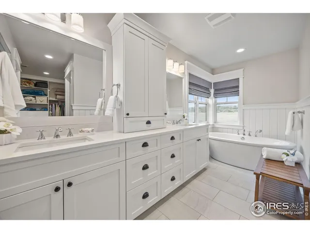 a bathroom with a sink double vanity granite tub and a mirror