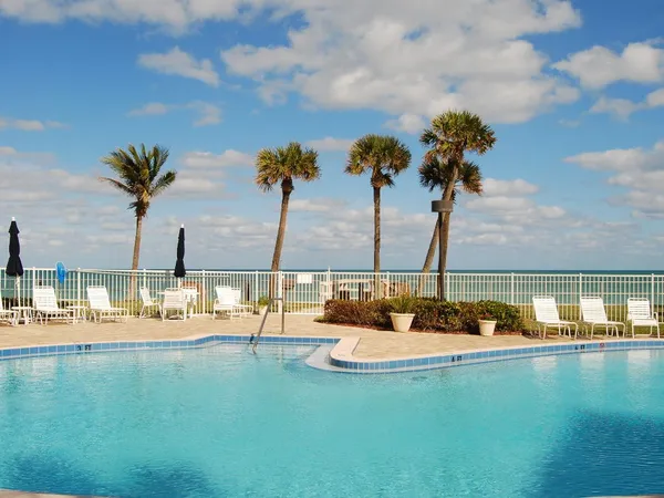 a view of a lake with couches and palm trees