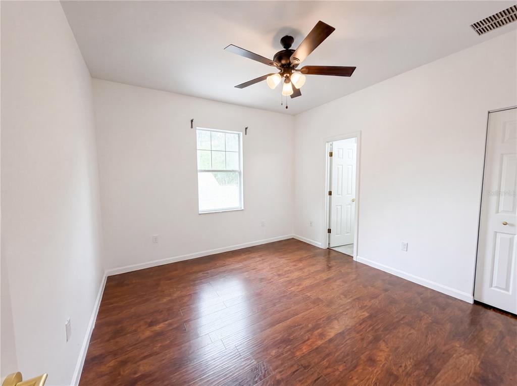 9405 Southwest 31st Lane Gainesville, FL 32608 - Photo 4 of 30 an empty room with wooden floor chandelier fan and windows