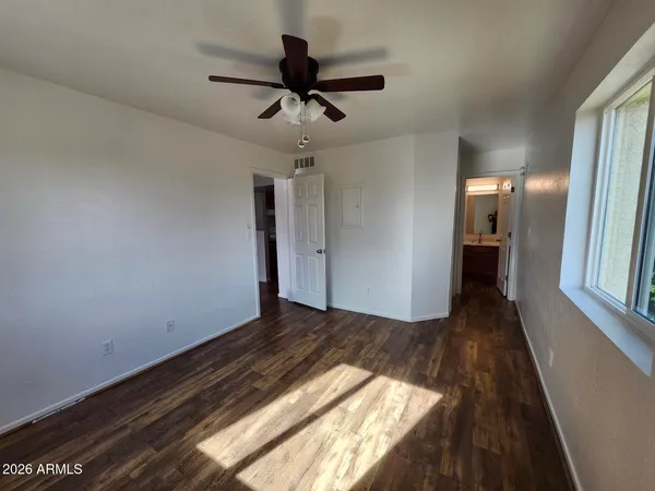 a view of empty room with wooden floor and fan