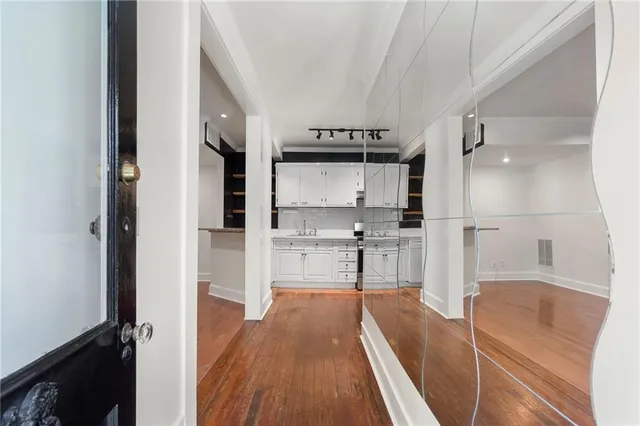 a view of an empty room and a kitchen with wooden floor and a window