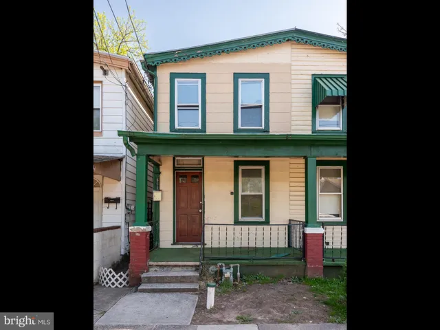 a view of brick house with a small yard and large tree