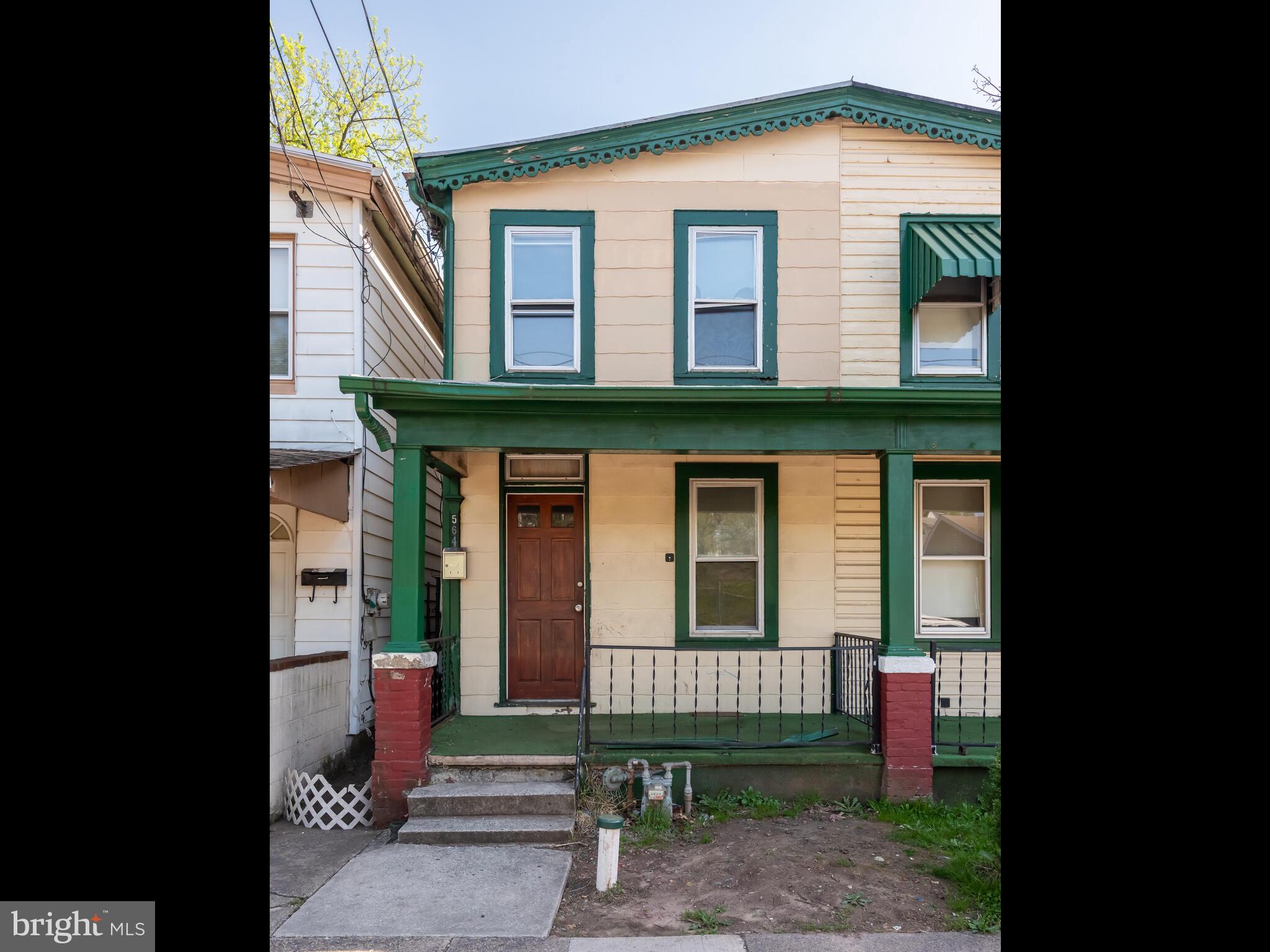 a view of brick house with a small yard and large tree