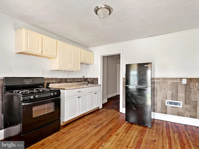 a kitchen with granite countertop a stove a refrigerator and a wooden floor