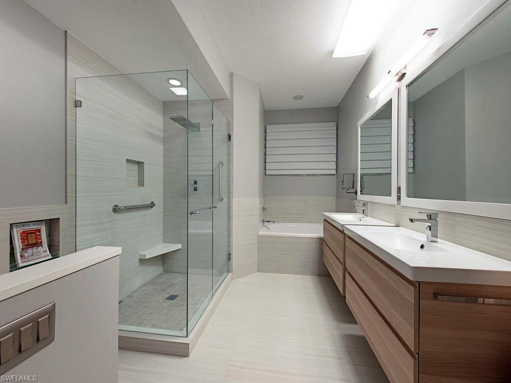 7120 Timberland Circle, Unit 202 Naples, FL 34109 - Photo 5 of 12 a bathroom with a double vanity sink a toilet a mirror and shower