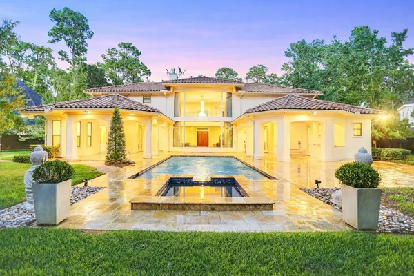 a front view of a house with swimming pool and glass top table and chairs