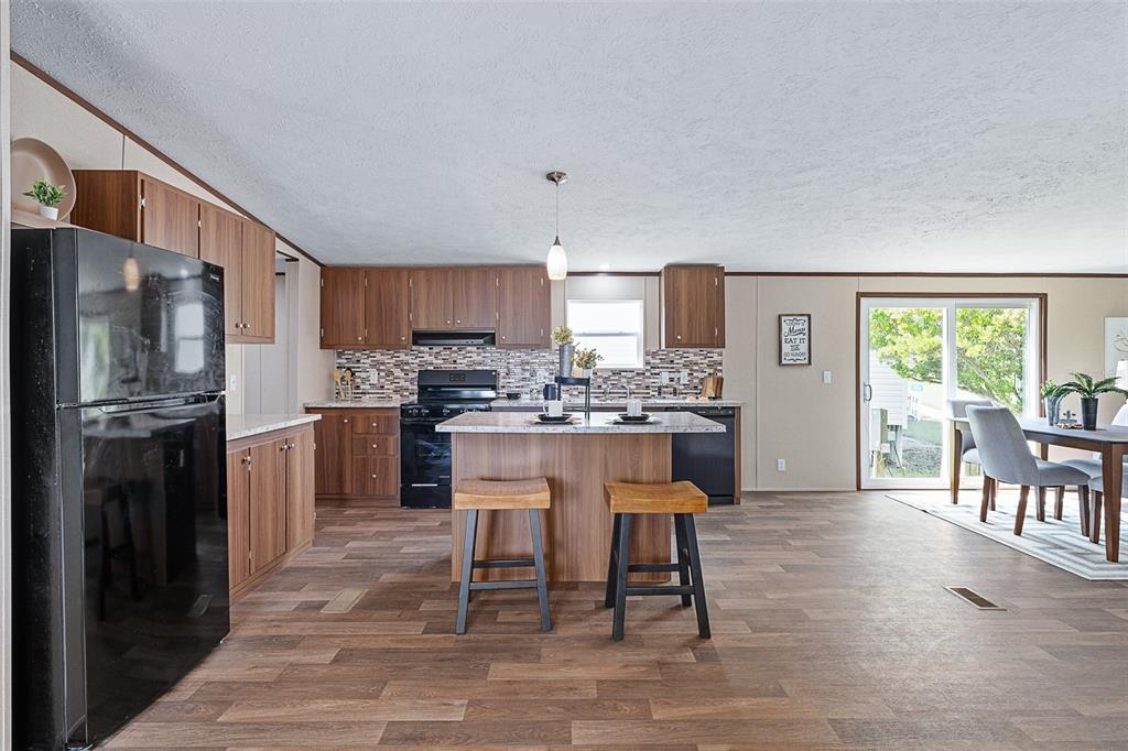 8150 Cherokee Road Bartow, FL 33830 - Photo 11 of 35 a kitchen with stainless steel appliances granite countertop a refrigerator a stove a sink a dining table and chairs with wooden floor