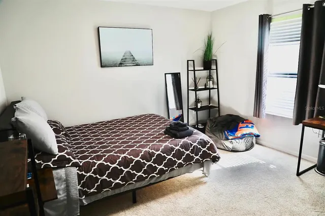 a bedroom with bed and a painting on the wall