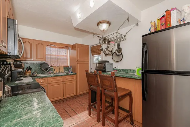a kitchen with stainless steel appliances granite countertop a refrigerator a stove top oven a sink and dishwasher a dining table with wooden floor