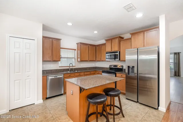 a kitchen with granite countertop stainless steel appliances a refrigerator a stove a sink cabinets and a dining table