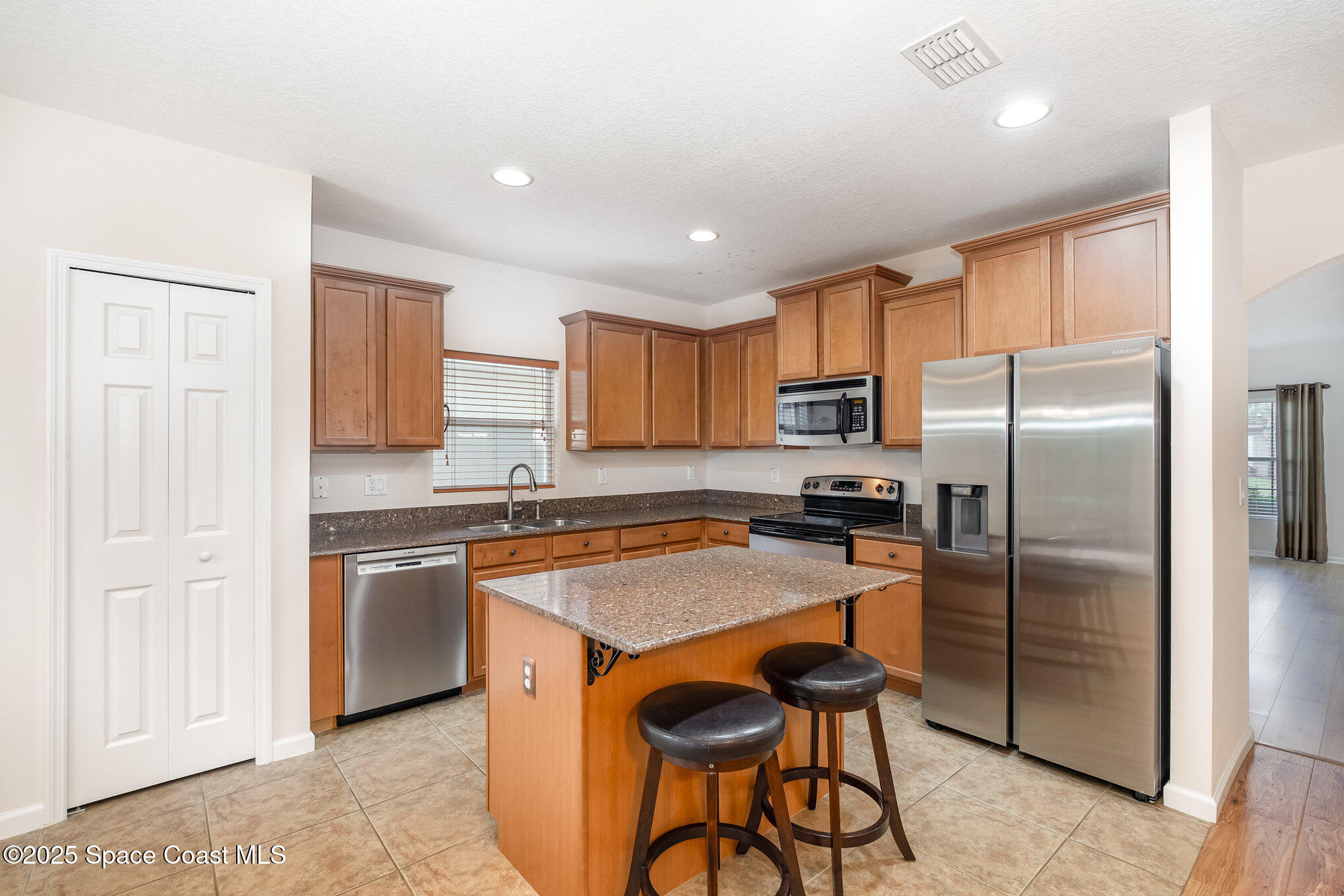 1517 Attilburgh Boulevard Melbourne, FL 32904 - Photo 4 of 15 a kitchen with granite countertop stainless steel appliances a refrigerator a stove a sink cabinets and a dining table