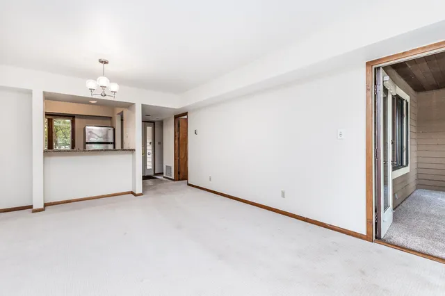 an empty room with chandelier fan and windows