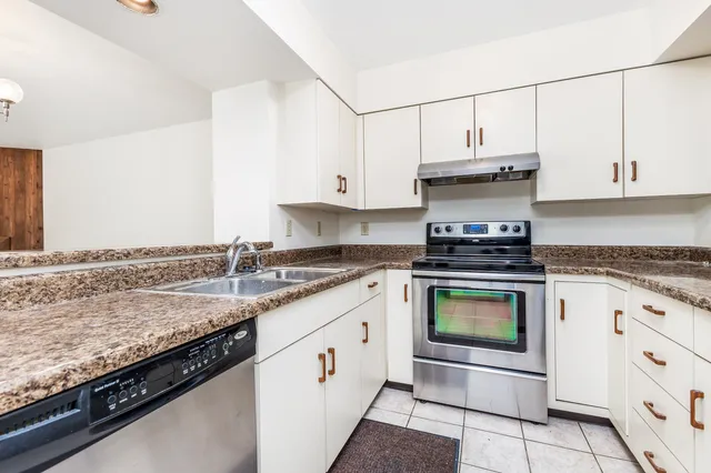a kitchen with granite countertop a stove sink and cabinets