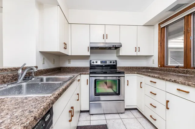 a kitchen with granite countertop a sink a stove and cabinets