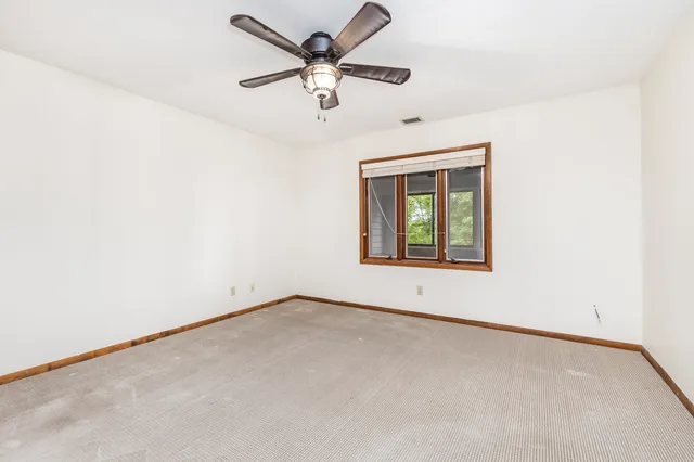 an empty room with a window and a fan