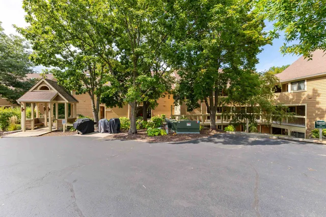 a view of a house with large tree and wooden fence