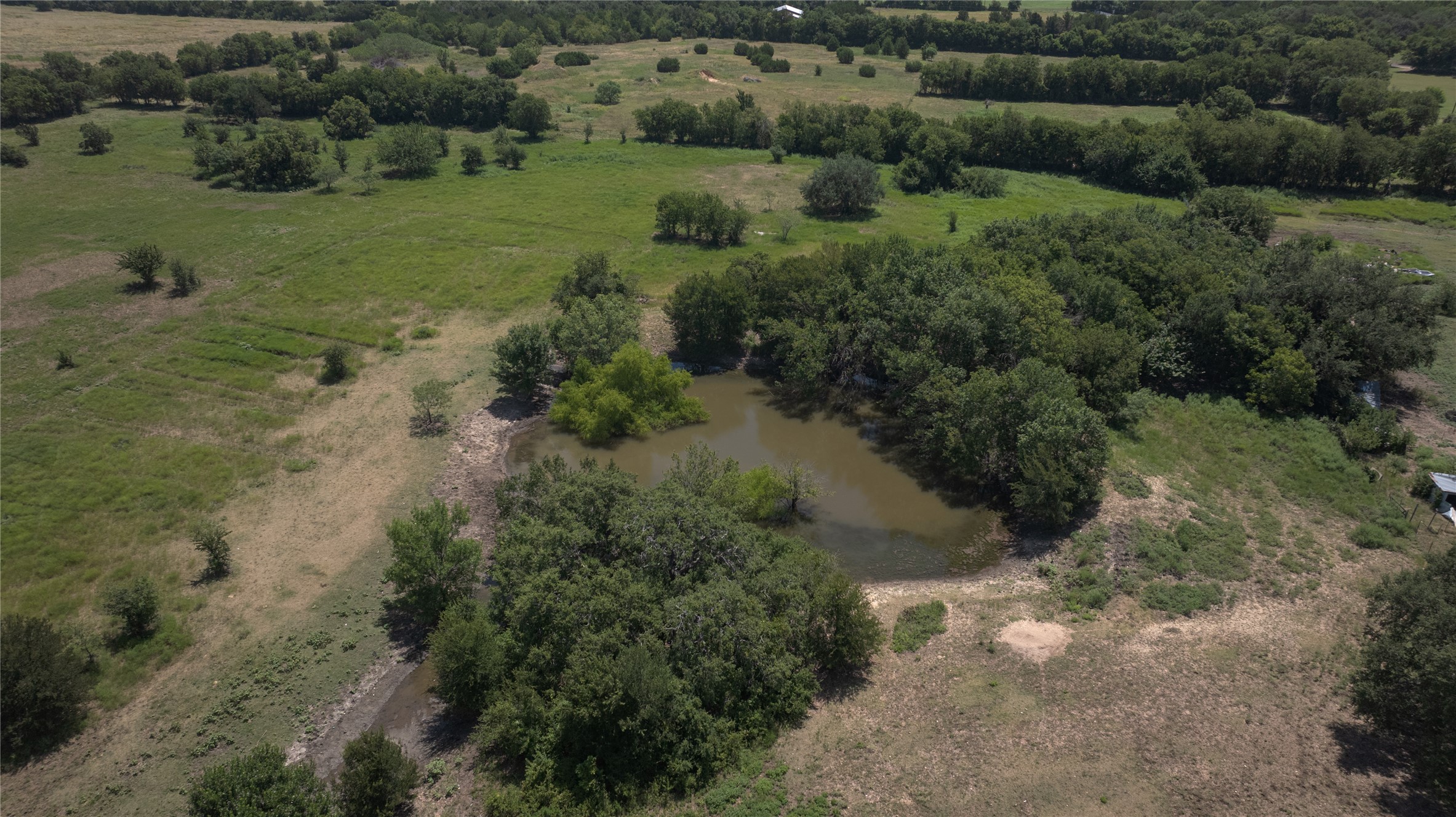 Tbd Summers Mill Road Belton, TX 76513 - Photo 14 of 21 A tranquil pond and verdant landscape define this expansive rural property, perfect for outdoor enthusiasts.