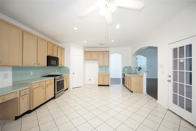 a large kitchen with stainless steel appliances granite countertop a sink and white cabinets