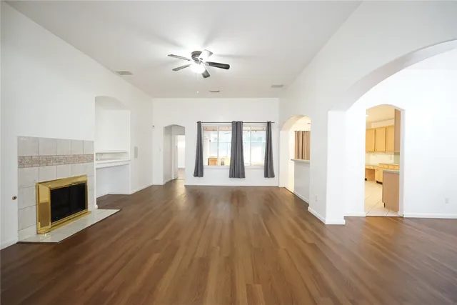 a view of an empty room with wooden floor fireplace and a window