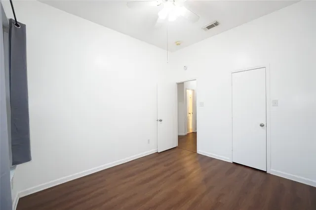 an empty room with wooden floor and a ceiling fan