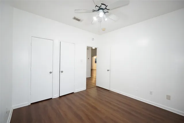 an empty room with wooden floor and fan
