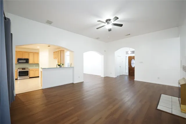 a view of a kitchen and an empty room with wooden floor and a kitchen
