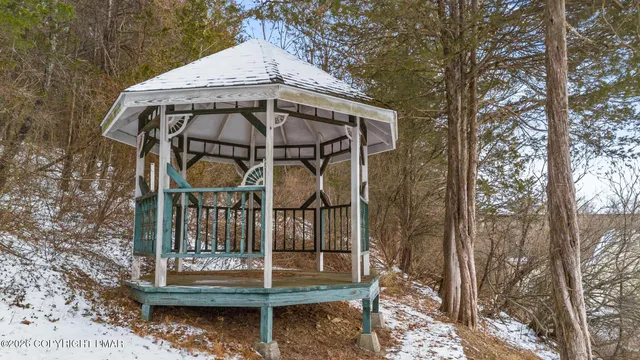 a view of a wooden house with large trees and wooden fence
