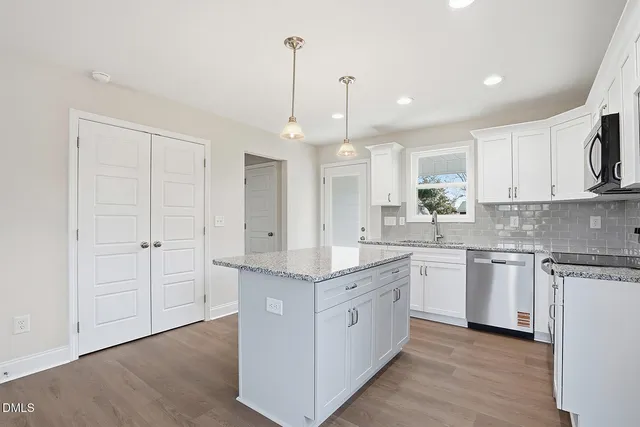 a kitchen with stainless steel appliances granite countertop a sink a stove and a refrigerator