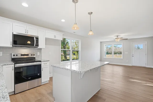 a kitchen with stainless steel appliances granite countertop a stove a sink and a microwave