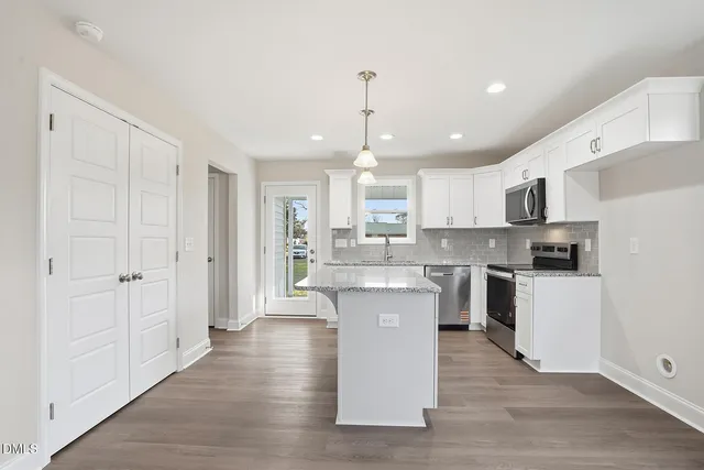 a kitchen with kitchen island white cabinets and stainless steel appliances