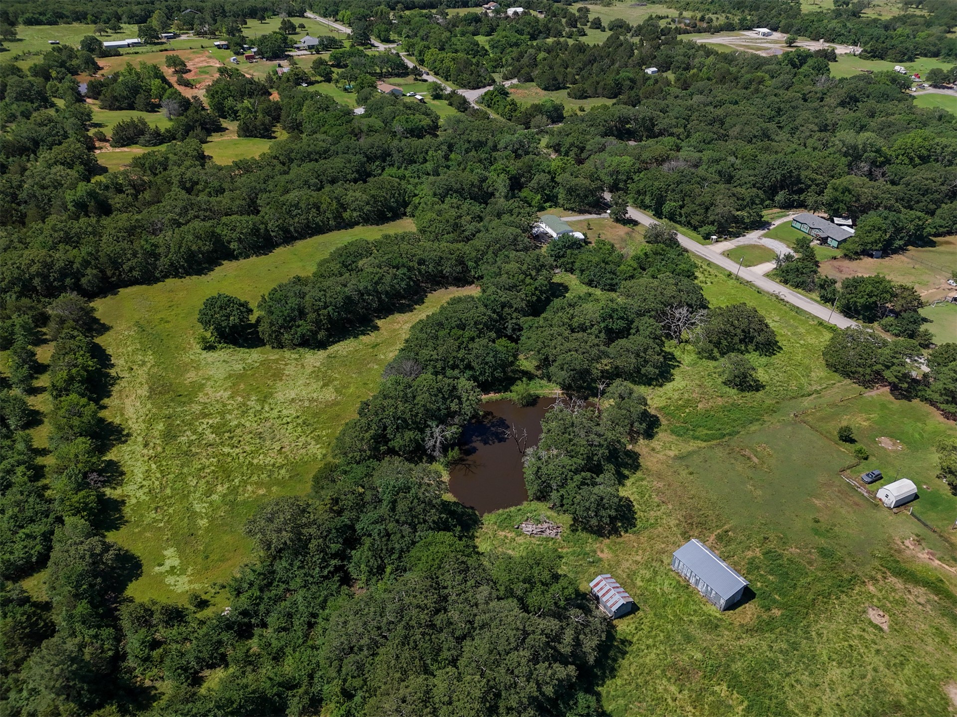 0 Harvey Road Ardmore, OK 73401 - Photo 7 of 10 Expansive acreage featuring abundant mature trees, open grassy areas, a natural pond, and two utility outbuildings