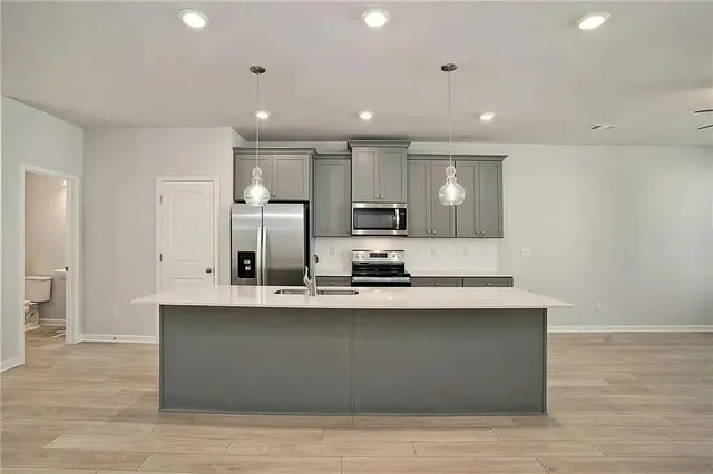 a large kitchen with stainless steel appliances a large counter top a sink and a refrigerator