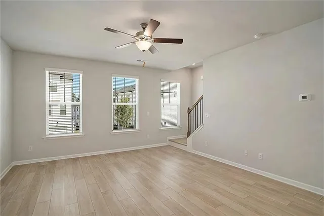 an empty room with wooden floor fan and windows