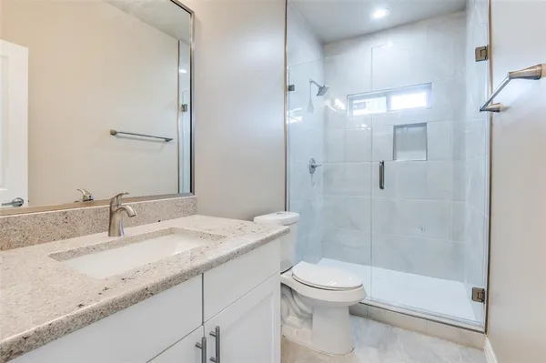 a bathroom with a granite countertop sink a toilet and shower