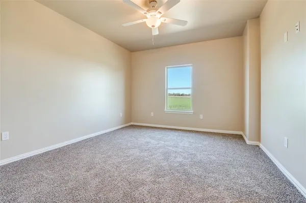 an empty room with a window and a ceiling fan